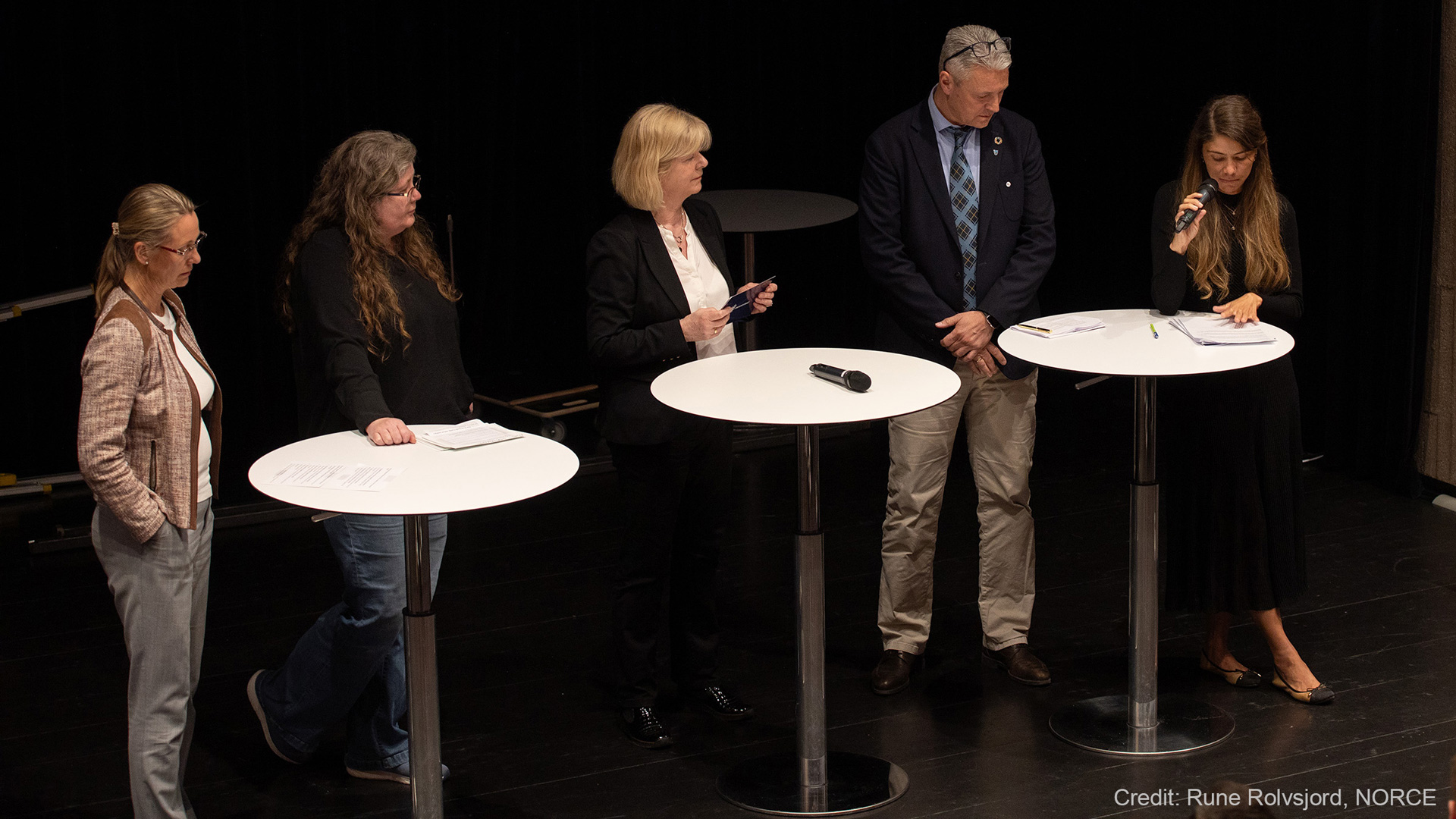 4 women and 1 man having a panel discussion on stage.